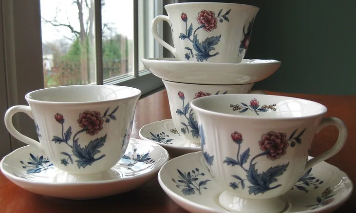 Floral teacups stacked by a window